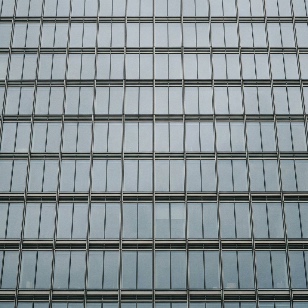 The upper facade of a City of London tower, repeating glass and steel bays seen from below
